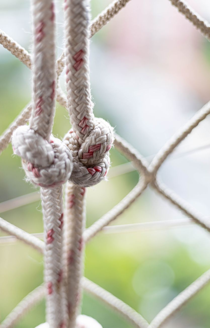 Detailed view of intertwined ropes forming secure knots in a net, with soft blurred background.