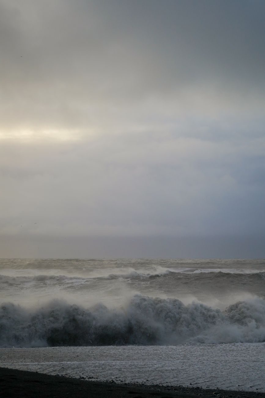 Powerful ocean waves crash under a moody, stormy sky, capturing nature's raw beauty and force.